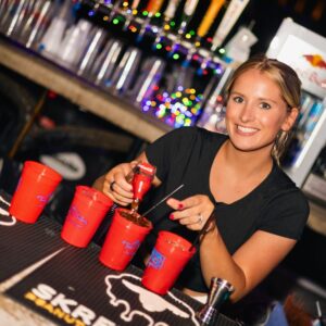 Bartender pouring drinks into red Tin Roof souvenir cups during Thursday Cup Night in St. Louis.