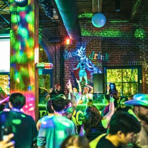 Crowd dancing under colorful lights at Tin Roof St. Louis while the DJ plays on stage during Thursday Cup Night.